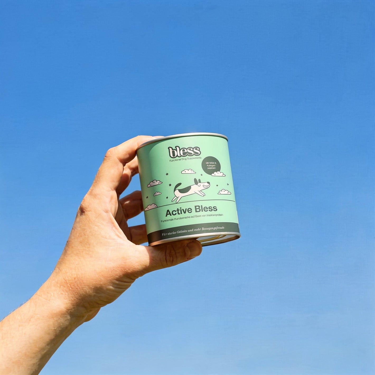 Hand hält eine Active Bless Dose vor blauem Himmel